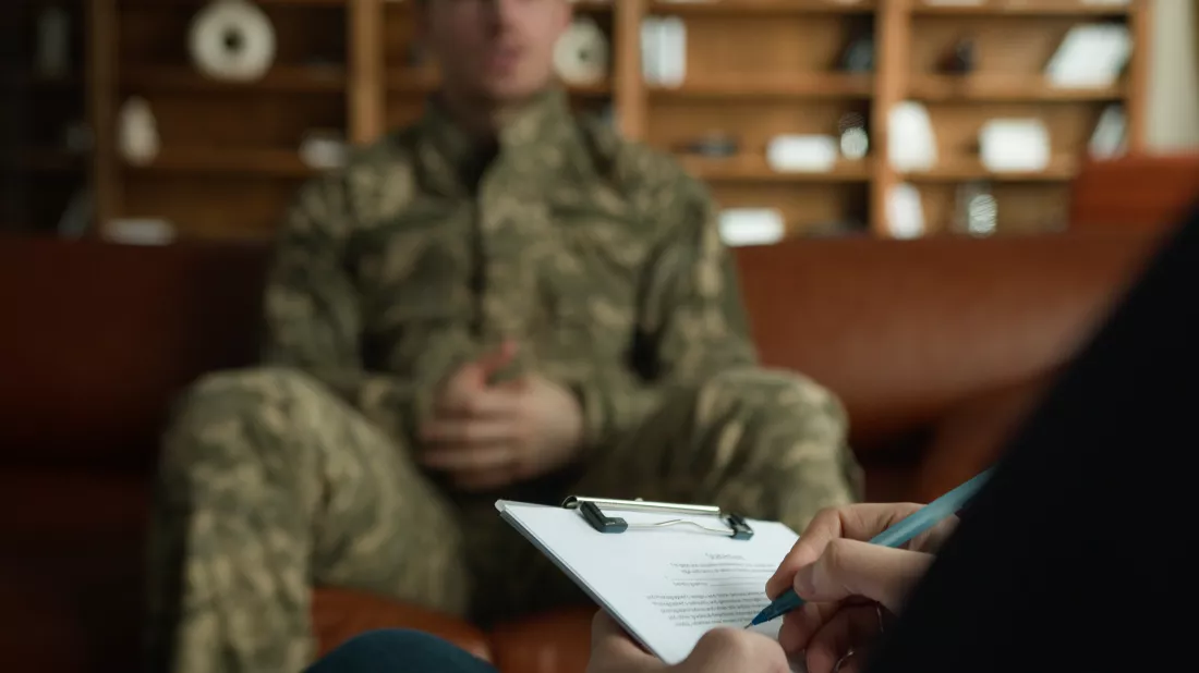 unknown-psychologist-taking-notes-writing-pen-clipboard-listen-caucasian-male-officer-camouflage